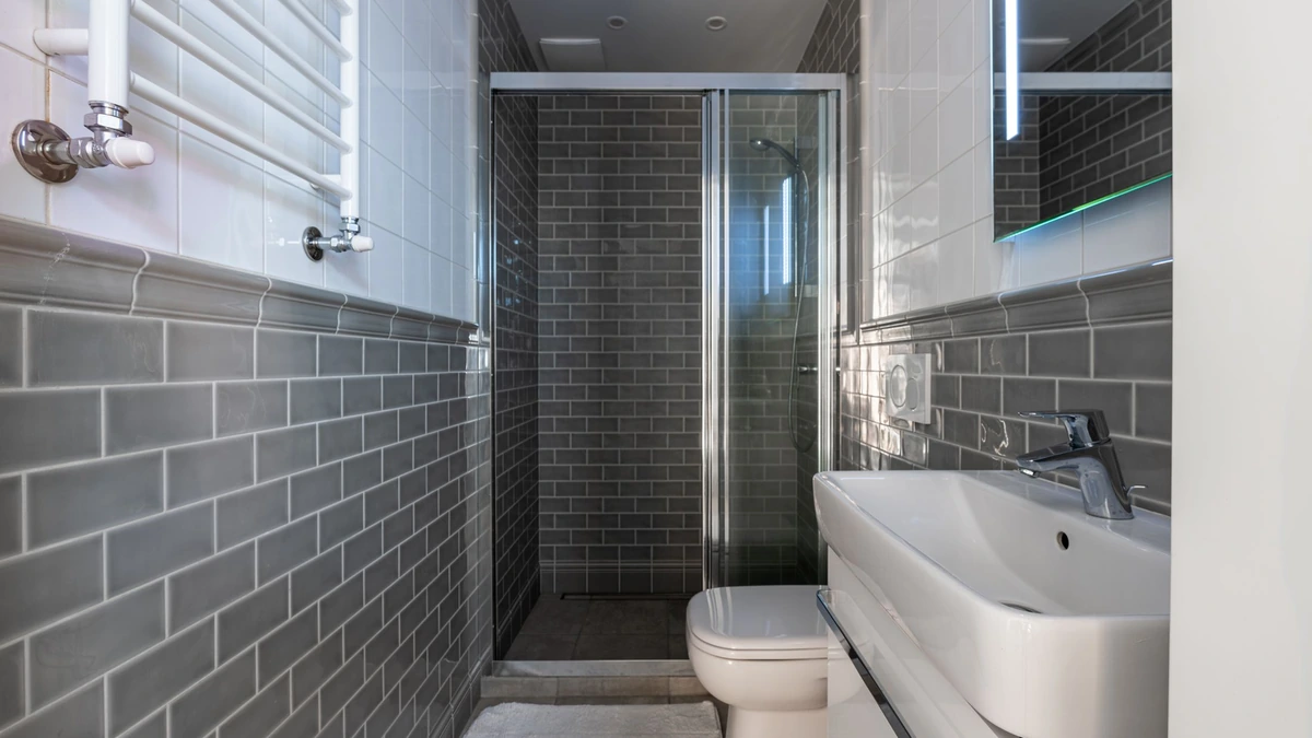 A glossy white refinished freestanding tub in a bright tiled bathroom, no people