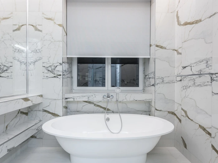 A close daylight detail of a freshly reglazed white tub rim with a clean tile wall behind it, no people