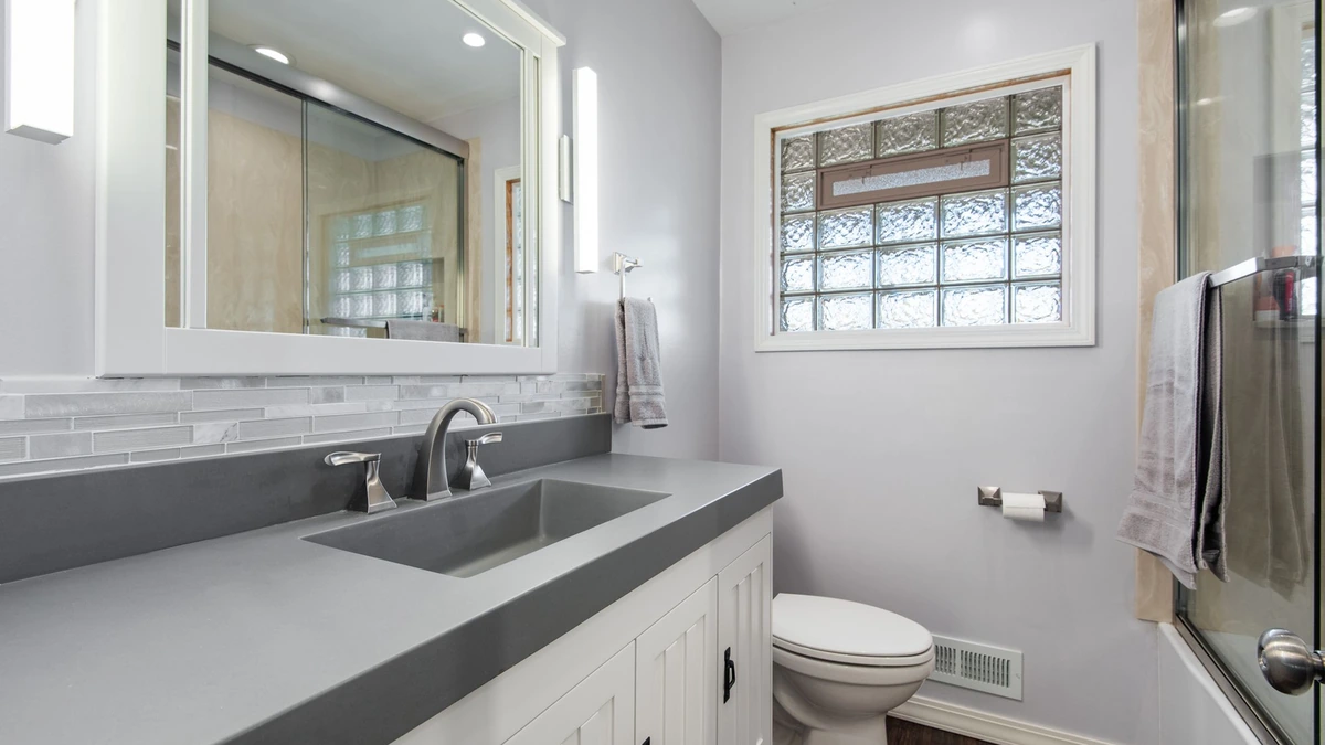 A glossy white refinished freestanding tub in a bright tiled bathroom, no people