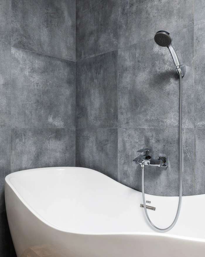 A resurfaced walk-in shower with clean tile and a glass panel